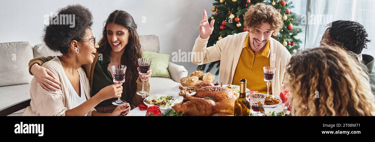 Fröhliche, multiethnische Familie, die am Feiertagstisch sitzt und ein fest genießt und aktiv redet, Banner Stockfoto