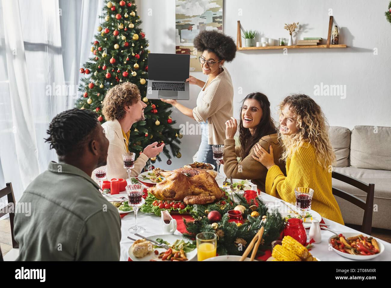 Multiethnische Familie spricht aktiv und lächelt die Laptop-Kamera an Feiertagstisch, Weihnachten Stockfoto