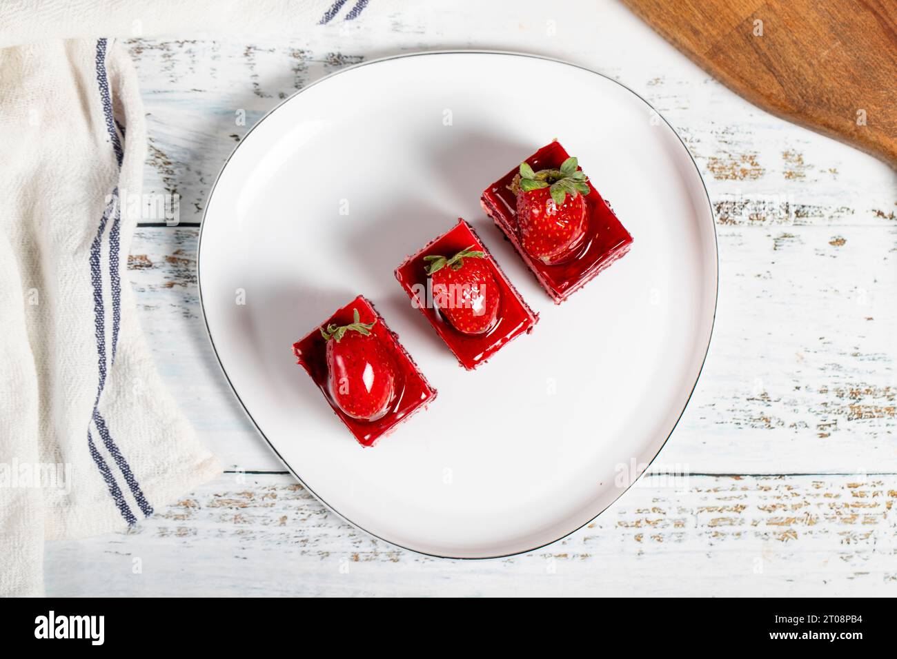 Kleine Scheiben Kuchen. Erdbeeren- und Sahnetuchscheiben auf einem Teller. Snack süße Speisen. Draufsicht Stockfoto