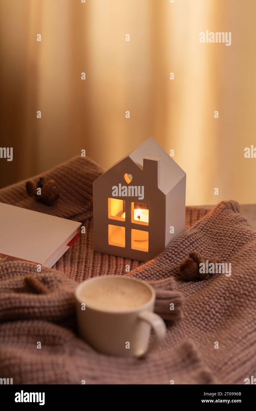 Ein Fotobuch, ein warmer Pullover, eine Tasse Kaffee, eine kleine brennende Kerze, warm, Wochenende, Herbst, Entspannung, Kleidung, ausruhen Stockfoto