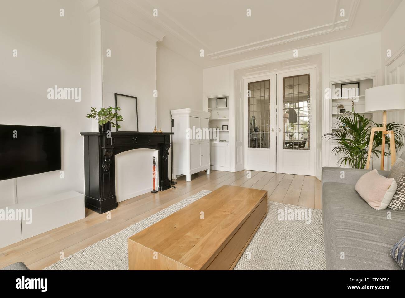 Innenraum des Wohnzimmers mit hölzernem Couchtisch vor dem Kamin und Fernseher an weißer Wand in einem modernen Apartment Stockfoto