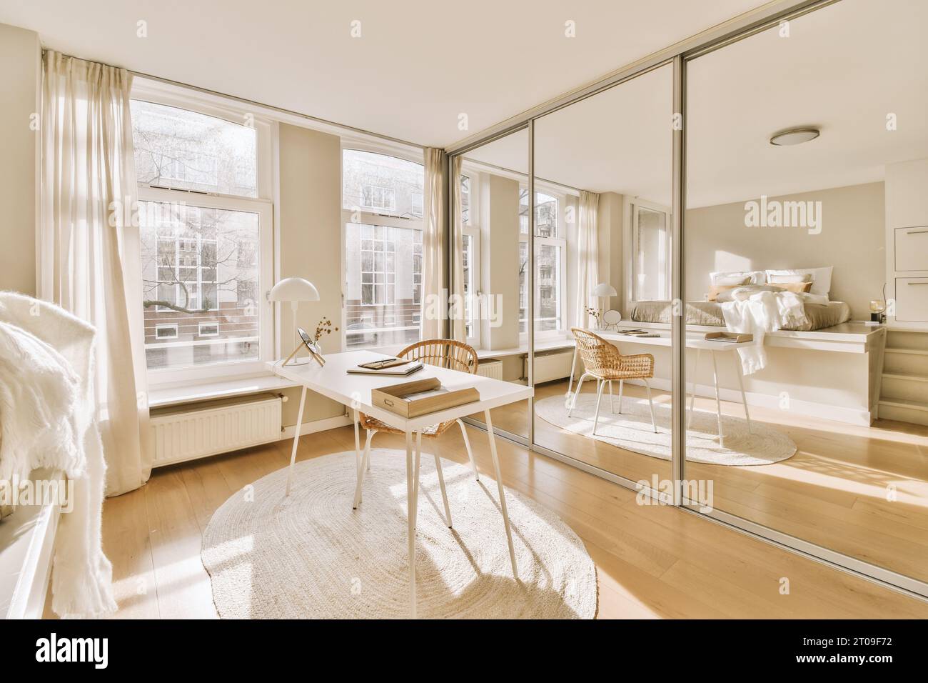 Inneneinrichtung eines stilvollen, geräumigen Schlafzimmers mit Schreibtisch am Fenster vor einem großen Spiegel in einem modernen Apartment Stockfoto