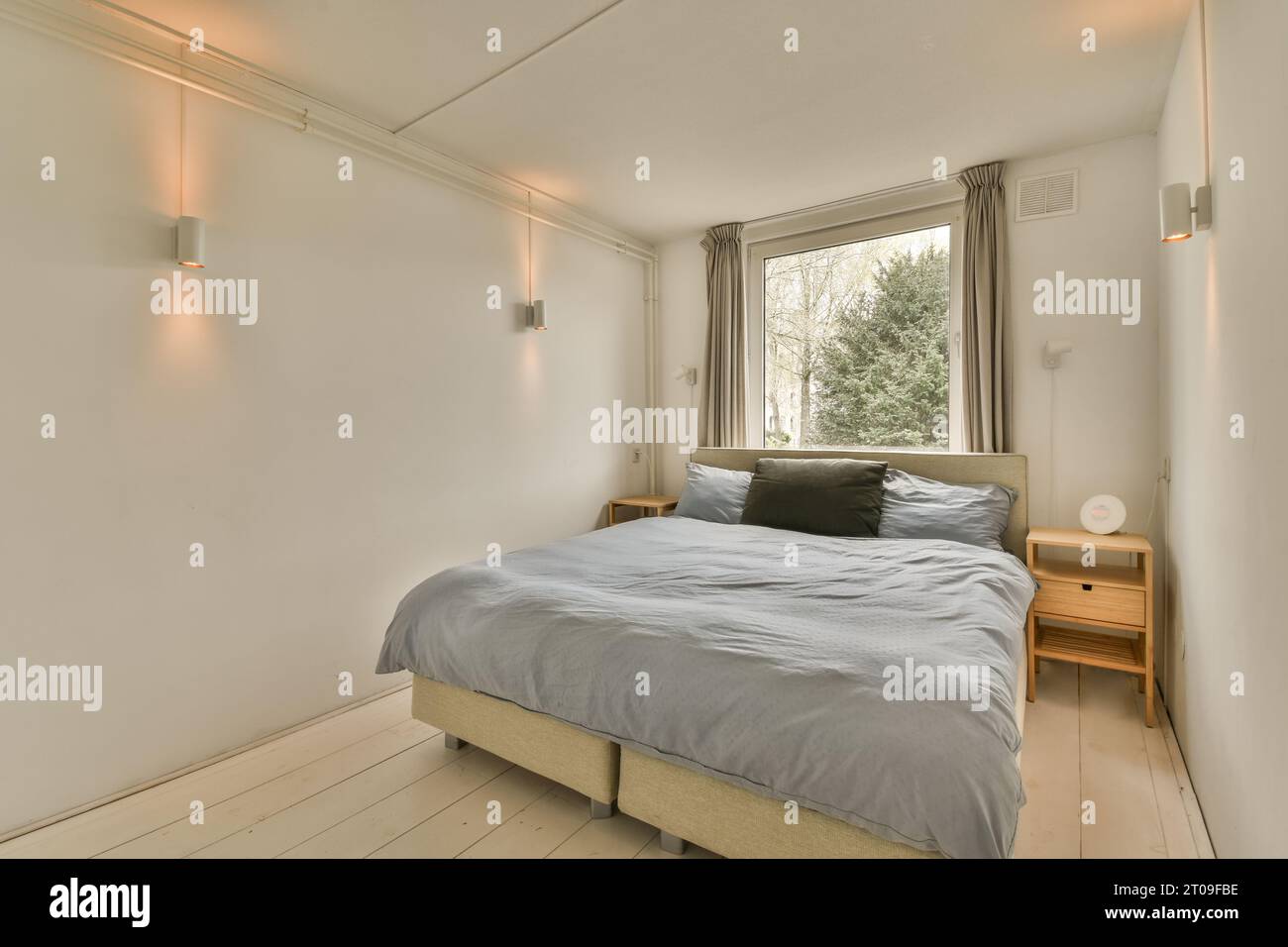 Innenausstattung mit beleuchteten Leuchten im modernen Schlafzimmer mit Bett vor dem Fenster Stockfoto