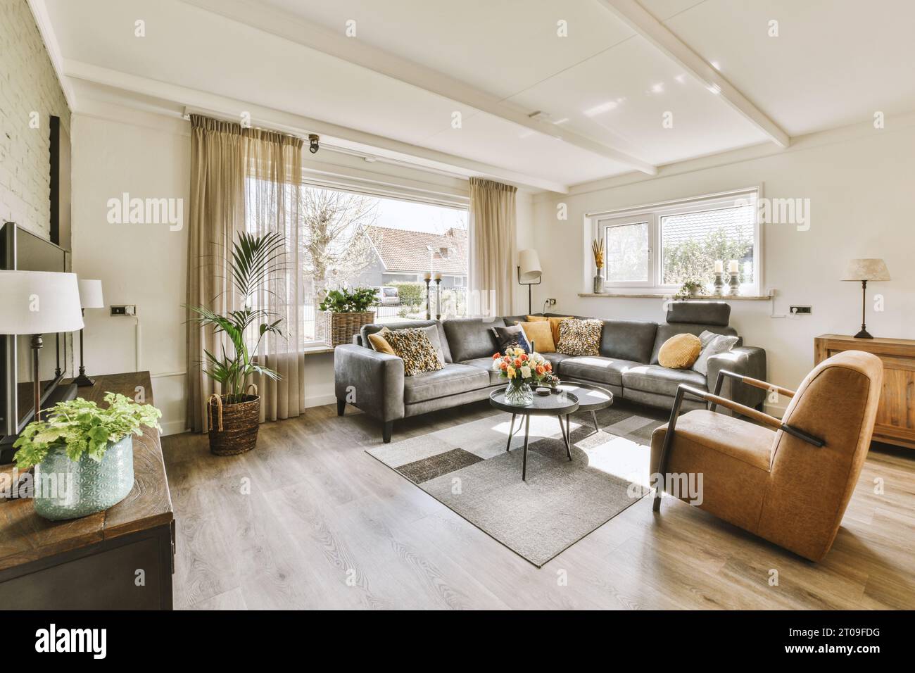 Das Innere des geräumigen Wohnzimmers mit Sofa und Couchtisch vor dem Fernseher durch ein großes Fenster zu Hause Stockfoto