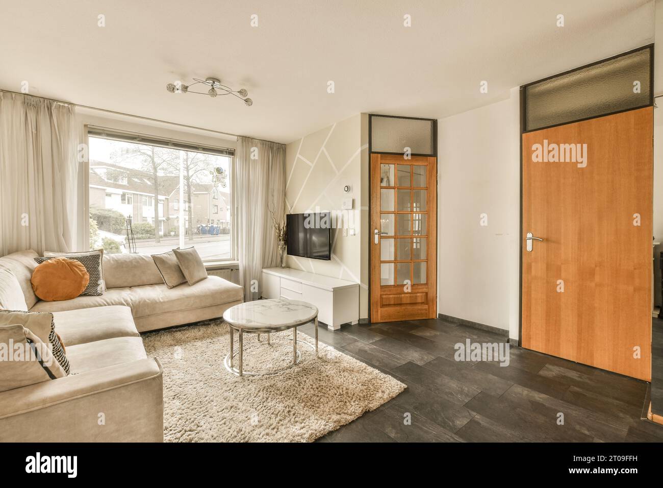 Komfortables Sofa und Couchtisch vor dem Fernseher im geräumigen Wohnzimmer des modernen Apartments Stockfoto