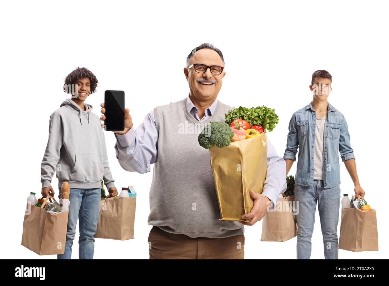 Lächelnder reifer Mann mit einem Smartphone, der vor jungen Männern mit Einkaufstaschen auf weißem Hintergrund steht Stockfoto
