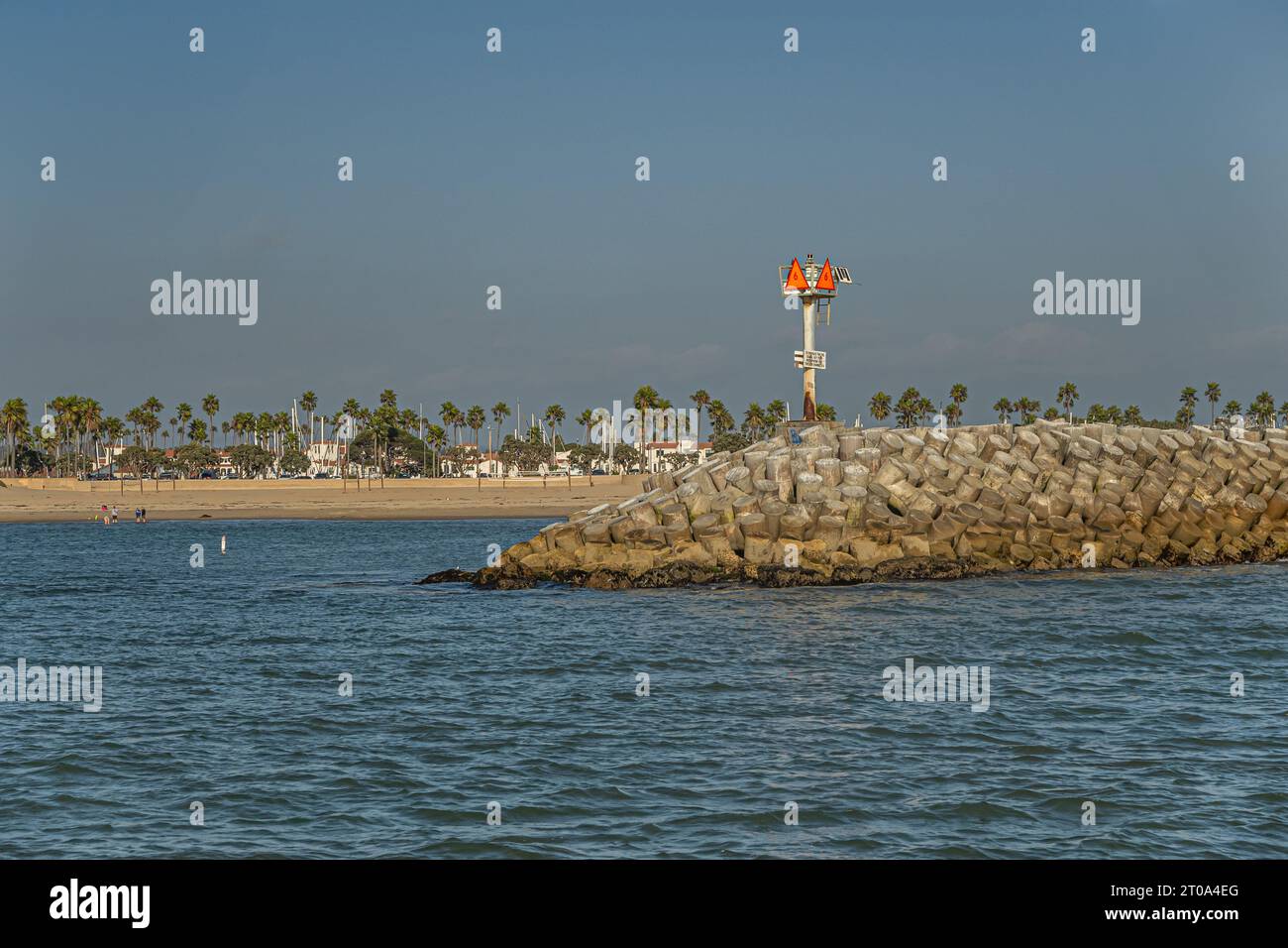 Ventura, CA, USA - 14. September 2023: Rotes Leuchtschild Nr. 6 am Eingang zum Hafen auf schweren Betonsteinen. Blauer Himmel und Meereswasser. Grüner Gürtel Stockfoto