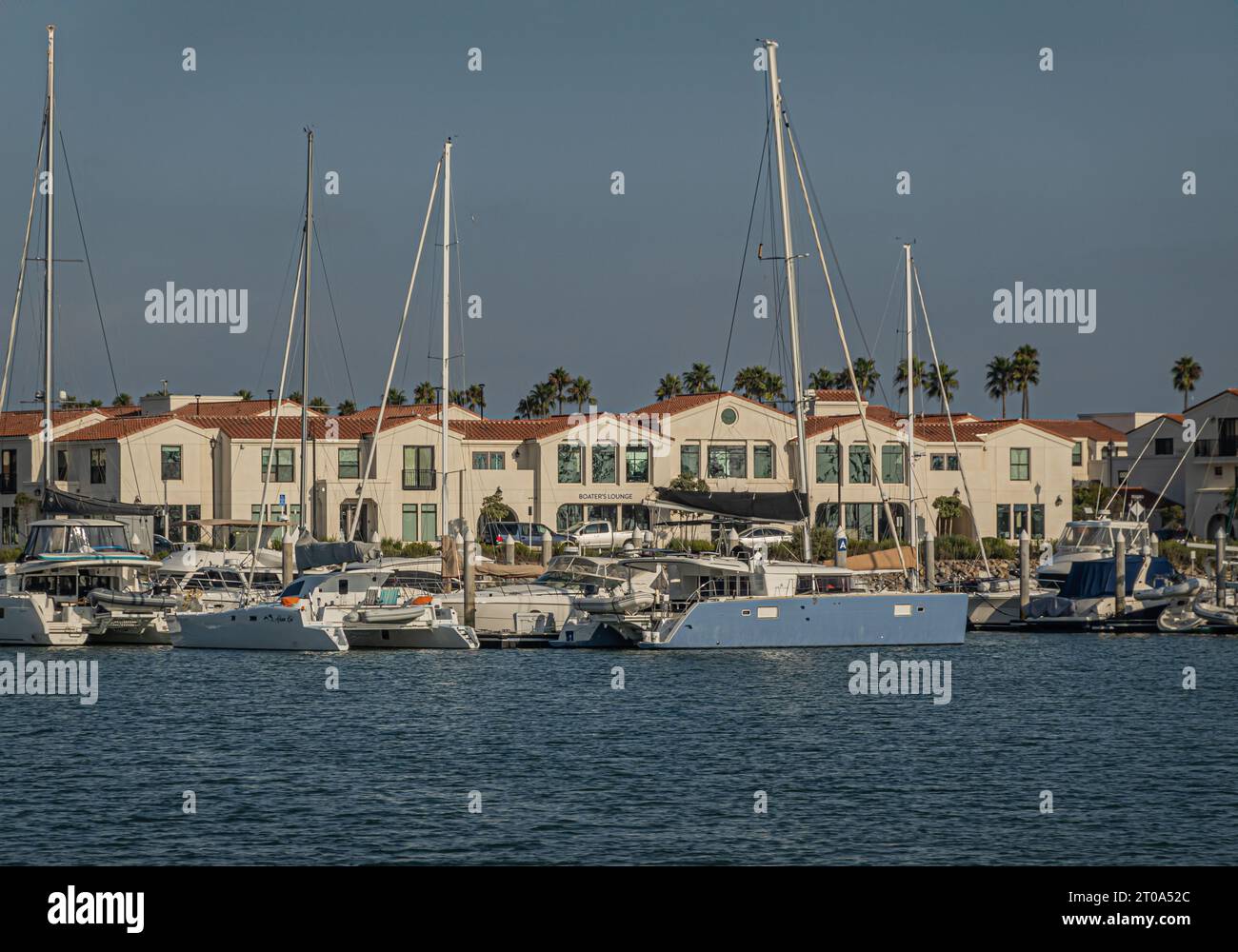 Ventura, CA, USA - 14. September 2023: Loungegebäude mit beigefarbener Fassade und rotem Dach zum Hafen hin, wo sich mehrere Yachten, Segel und Motor befinden Stockfoto