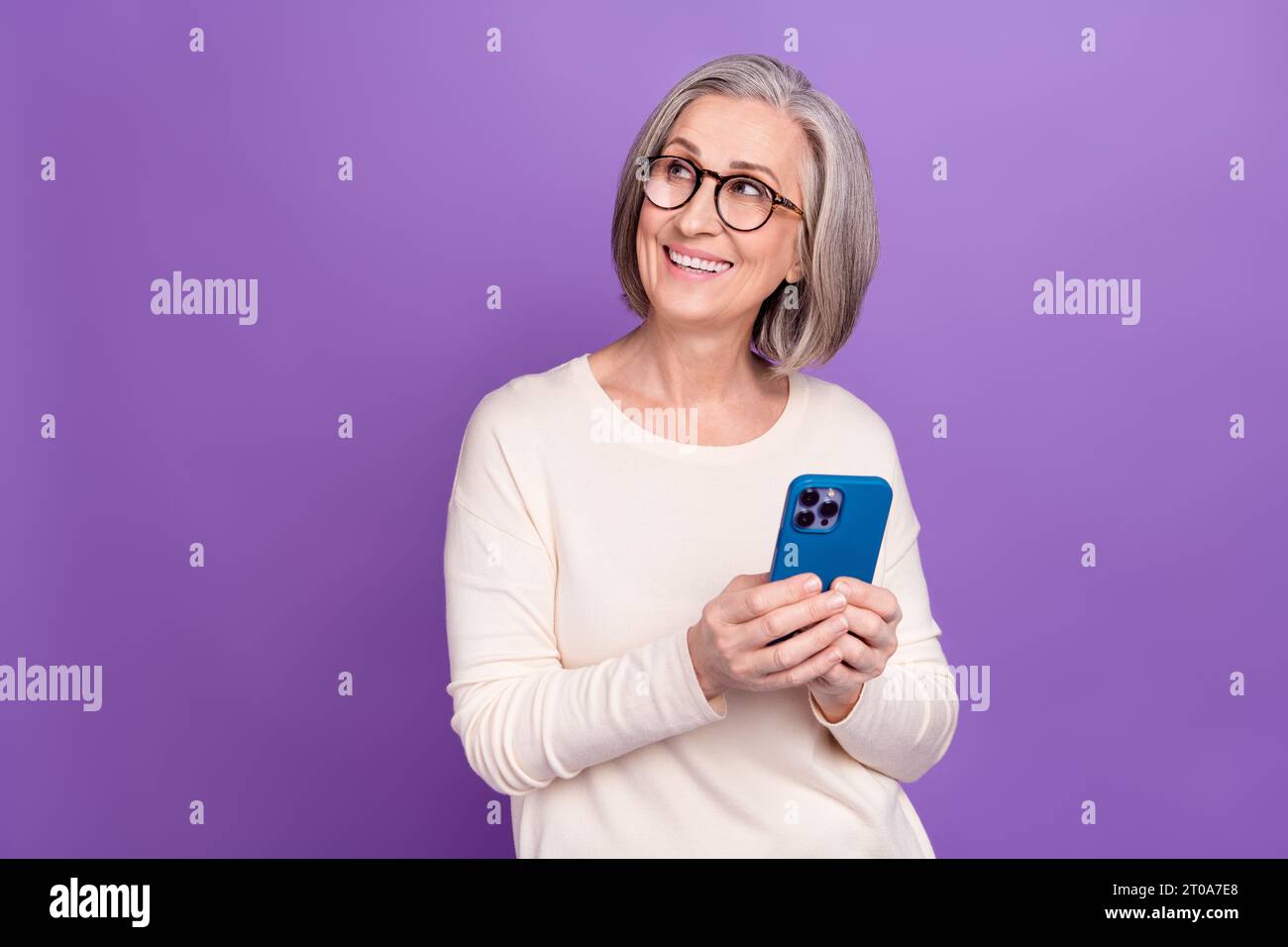 Foto von Rentnerin Frau, die iphone surft, Nachrichten lesen genießen Blick leer Raum überprüfen Wetter online isoliert über violettem Hintergrund Stockfoto