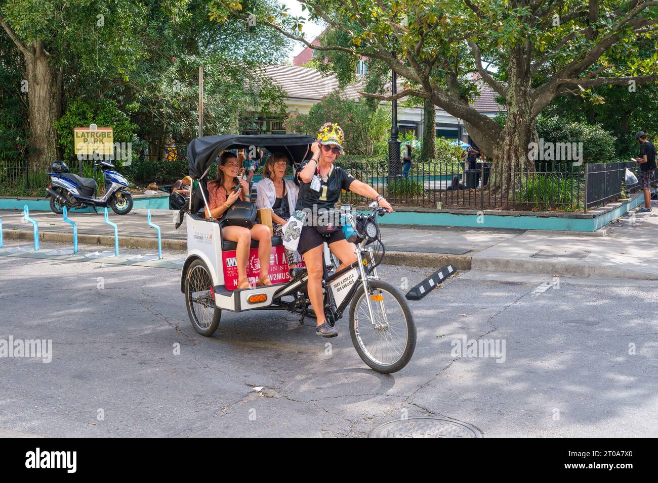 NEW ORLEANS, LA, USA - 24. September 2023: Reiseführer für Cajun Queen Tours bringt Touristen mit einem Dreiradtaxi im French Quarter Stockfoto