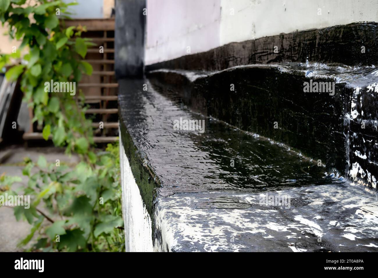 Reparatur der Stützwand des Gebäudes mit Abdichtungsprodukten. Reparatur einer alten, gerissenen, hinterfüllten Wand vor dem Eindringen von Wasser in das Gebäude. Stockfoto
