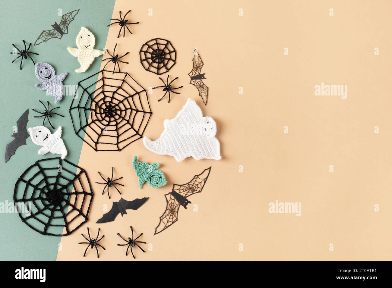 Halloween-Dekorationen, Geist, Spinnen, Fledermäuse, gestrickte Webs auf grünem und beigem Hintergrund. Halloween Grußkarte Mockup mit Kopierraum. Flach, oben Stockfoto