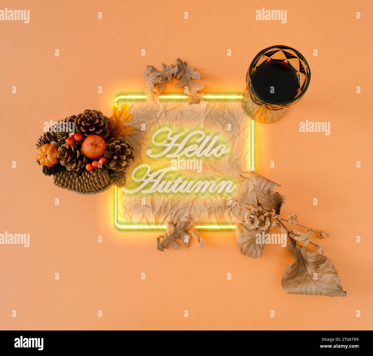 Kreatives Herbst- oder Herbst-fluoreszierendes Farblayout mit Blättern, kleinen Kürbissen und Glas Rotwein auf orangefarbenem Hintergrund. Minimales Naturkonzept. Stockfoto