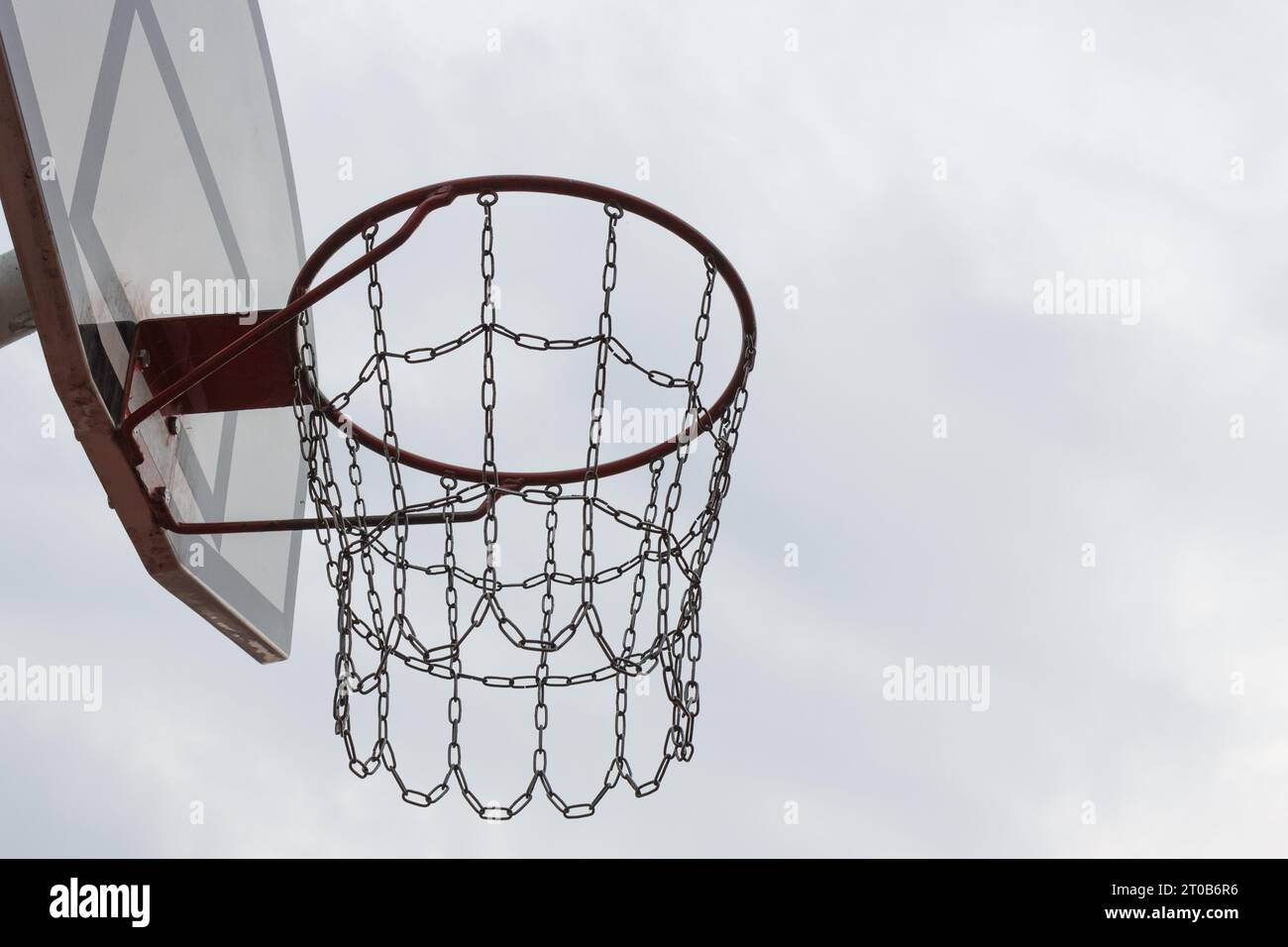 Der Basketballkorb auf der linken Seite des Fotos befindet sich auf einem Sportplatz im Freien vor hellem Hintergrund. Das Konzept eines aktiven Lebensstils Stockfoto