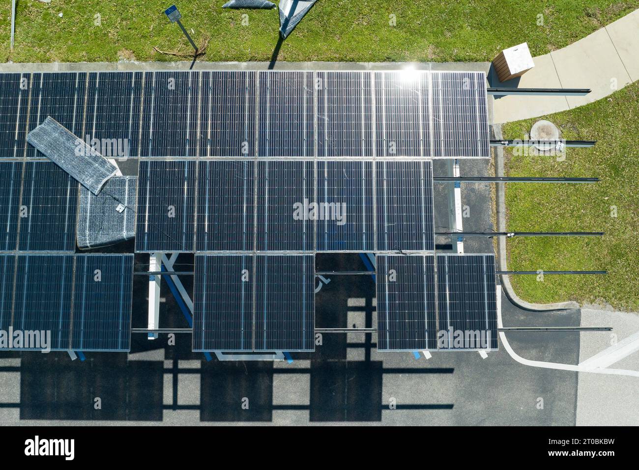 Ausfall der Photovoltaik-Technologie, die in die städtische Infrastruktur integriert ist. Hurrikan-Windschäden an Solarpaneelen, die als Schattendach über dem Parkplatz installiert sind Stockfoto