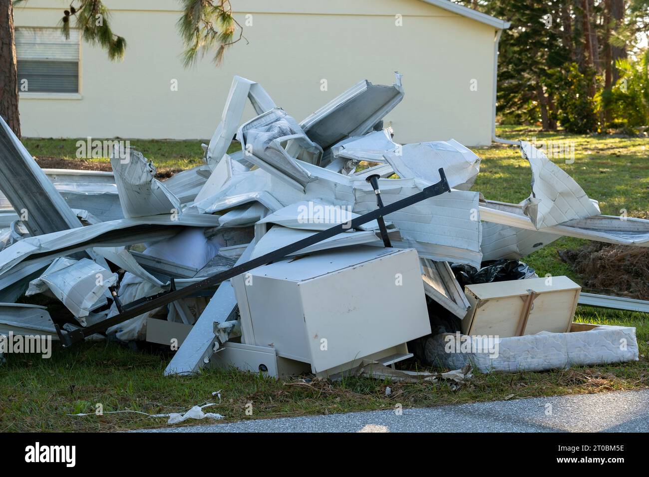 Müllhaufen auf der Straßenseite von stark beschädigten Häusern nach dem Hurrikan in Florida Wohnmobilgebiet. Folgen von Naturkatastrophen Stockfoto