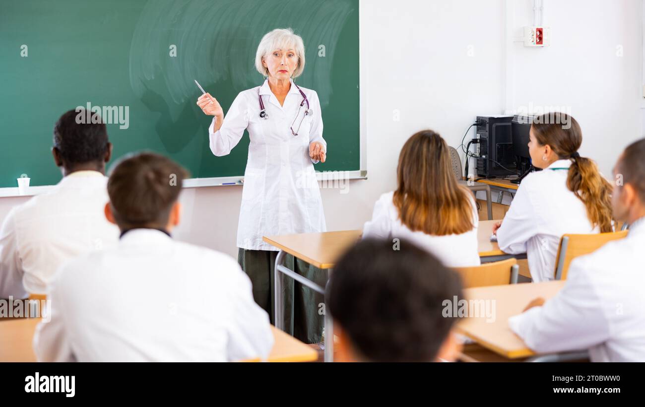 Ärztin erklärt erwachsenen Schülern im Universitätsunterricht neues Thema Stockfoto