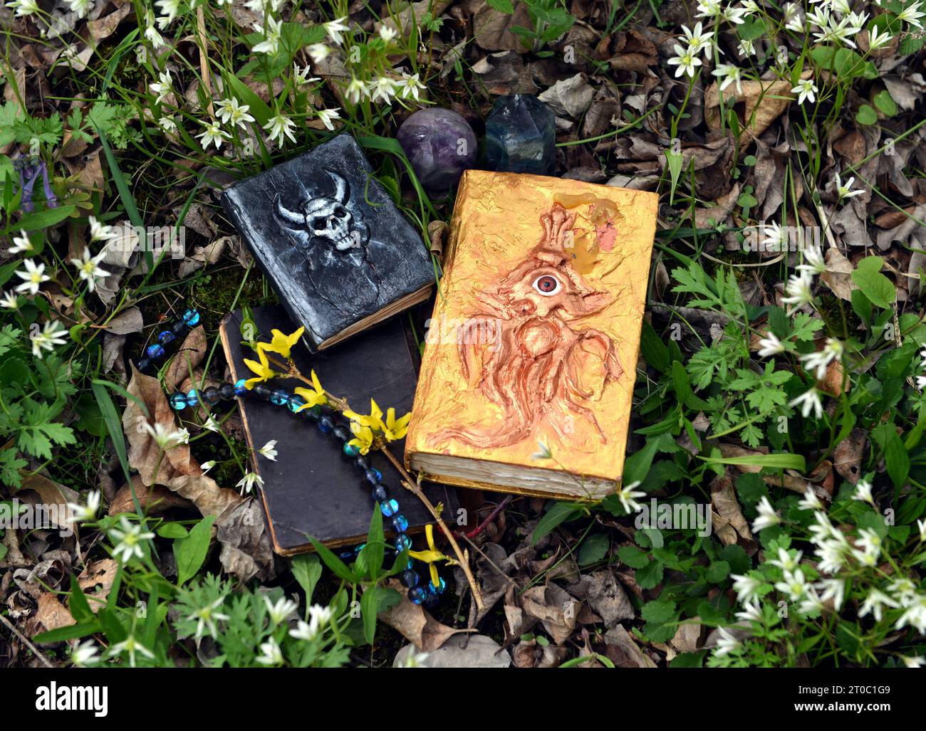Dekorierte Zauberbücher auf dem Gras im Garten. Okkultes, esoterisches und Wahrsagungsstilleben. Mystischer Hintergrund mit Vintage-Objekten Stockfoto