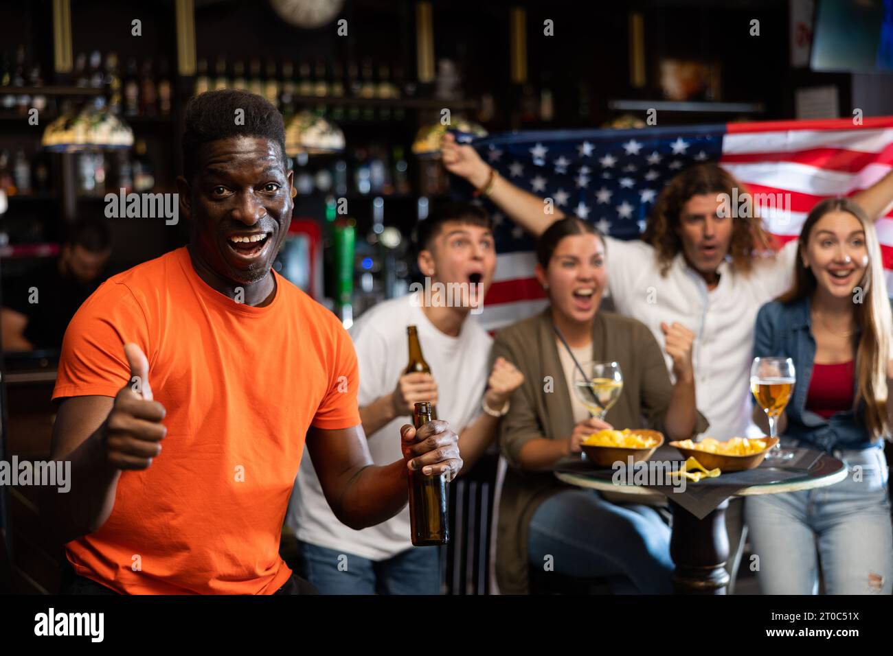 Aufgeregter afrikanischer Mann, der in der Sportbar für das beliebte amerikanische Baseballteam jubelt Stockfoto