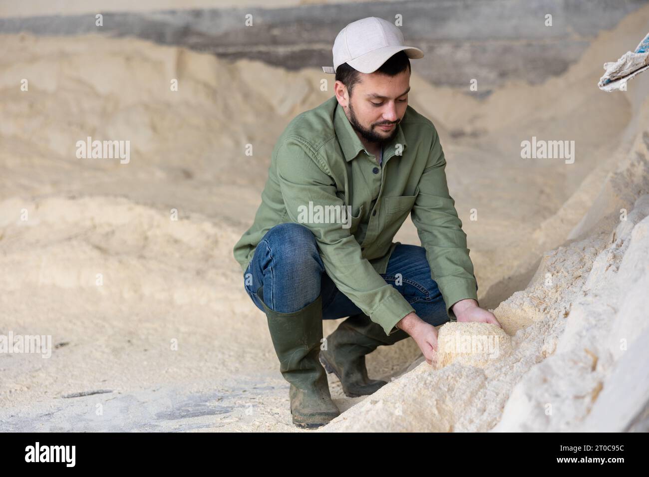 Bauer hockt auf einem Haufen Maismehl Stockfoto