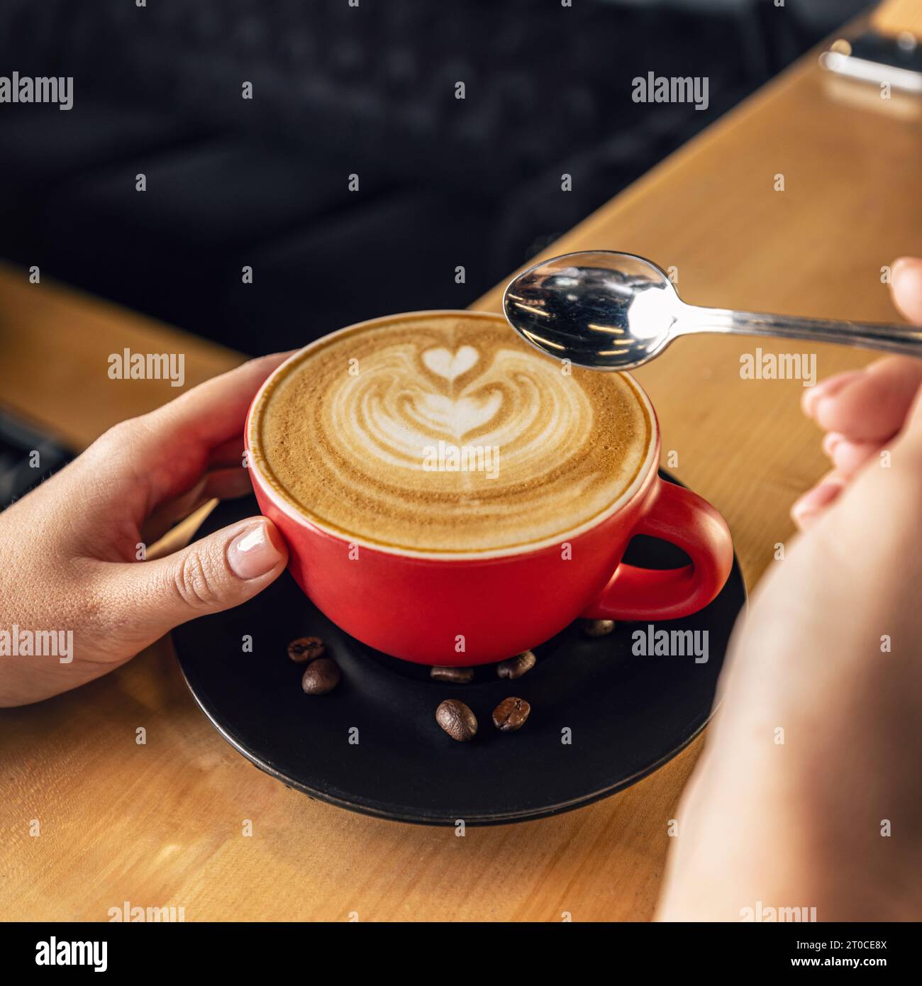 Frauenhände halten Latte Art Kaffeetasse Stockfoto