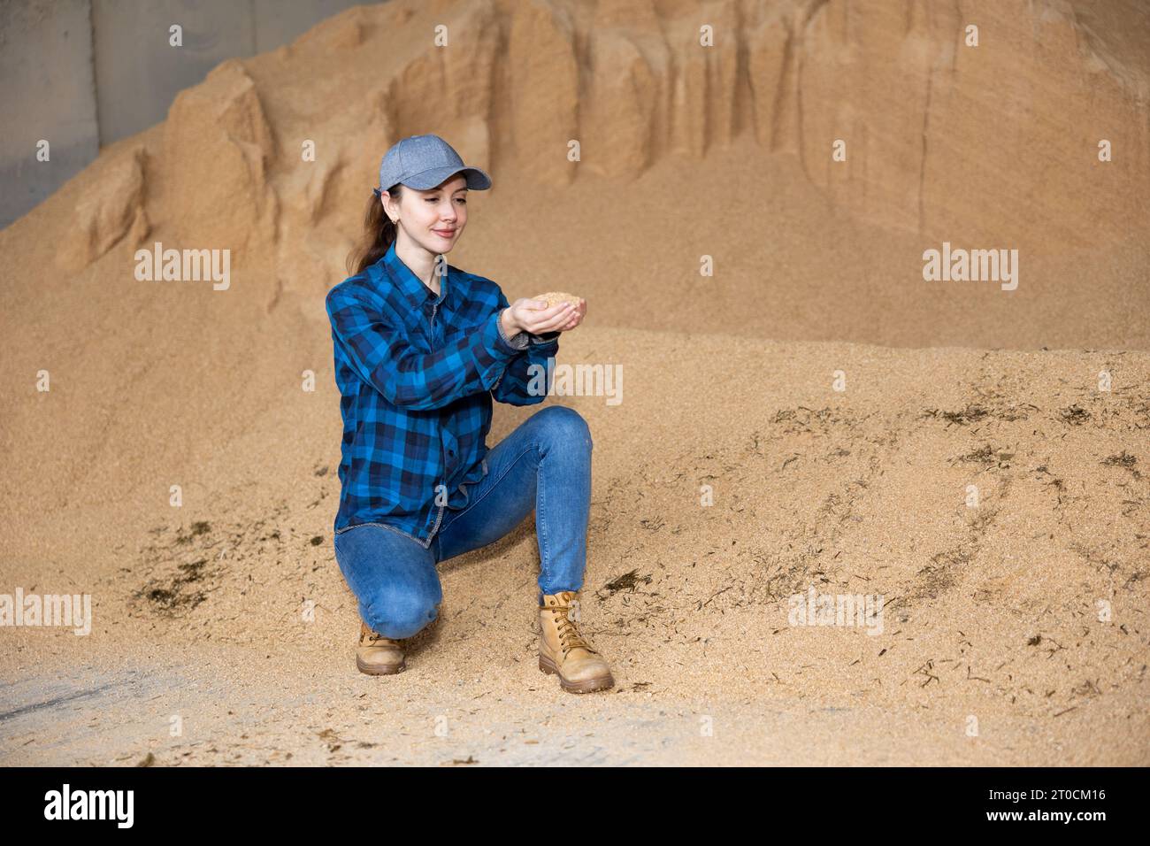 Bäuerin hockt auf einem Haufen Sojabohnenschalen Stockfoto