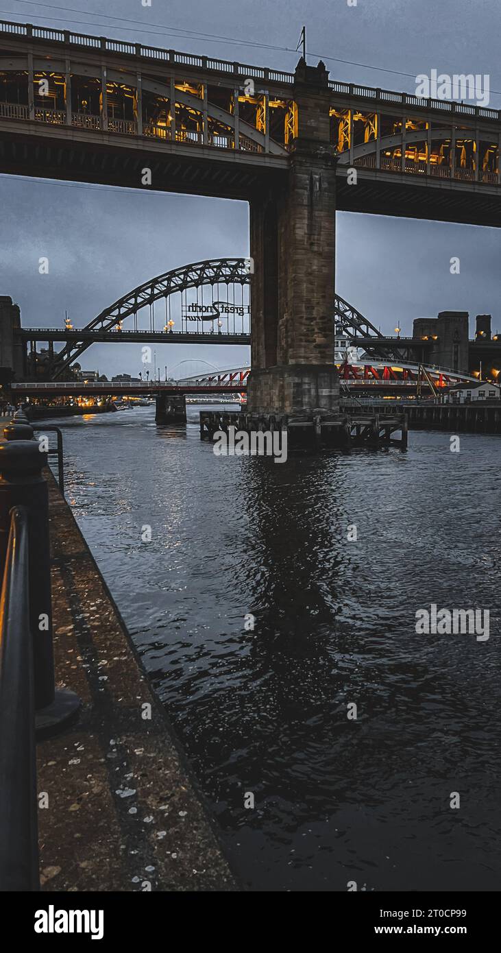 Dieses ruhige Bild zeigt eine majestätische Brücke, die hoch über einem wunderschönen Abendhimmel über einem friedlichen Fluss in Newcastle upon Tyne steht Stockfoto