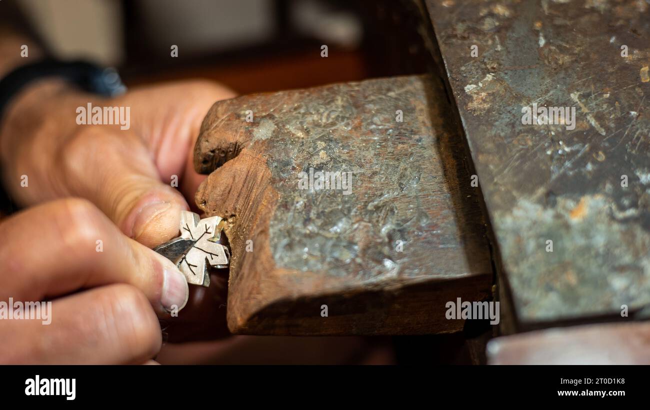 Goldschmied, der in seiner Goldschmiedewerkstatt mit einem Grain arbeitet und kreiert. Juwelier repariert ein silbernes Juwel. Stockfoto
