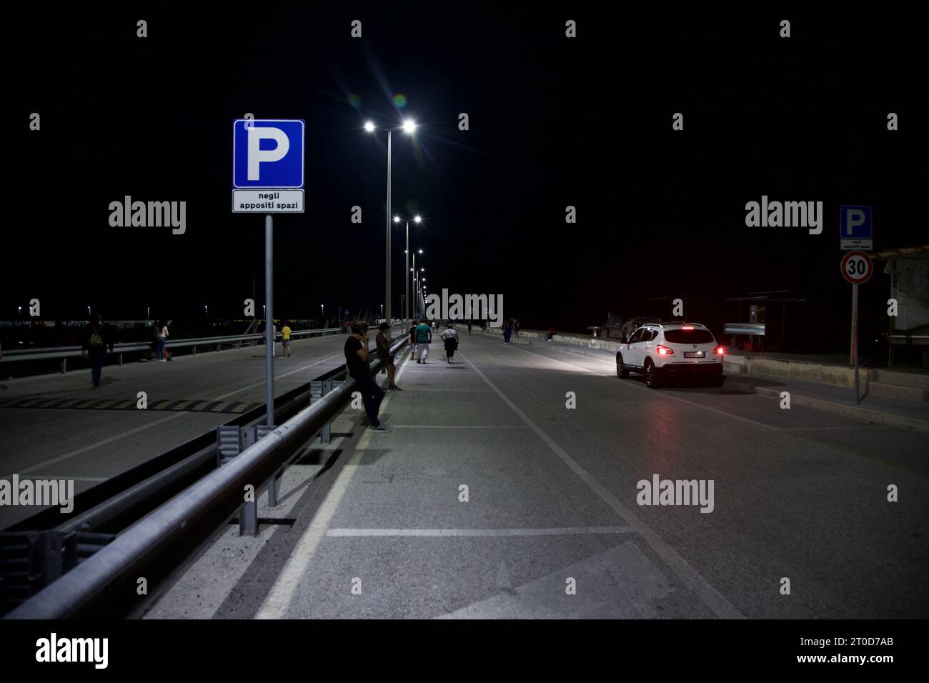 Straße auf einem Pier mit Leuten, die nachts vorbeikommen Stockfoto