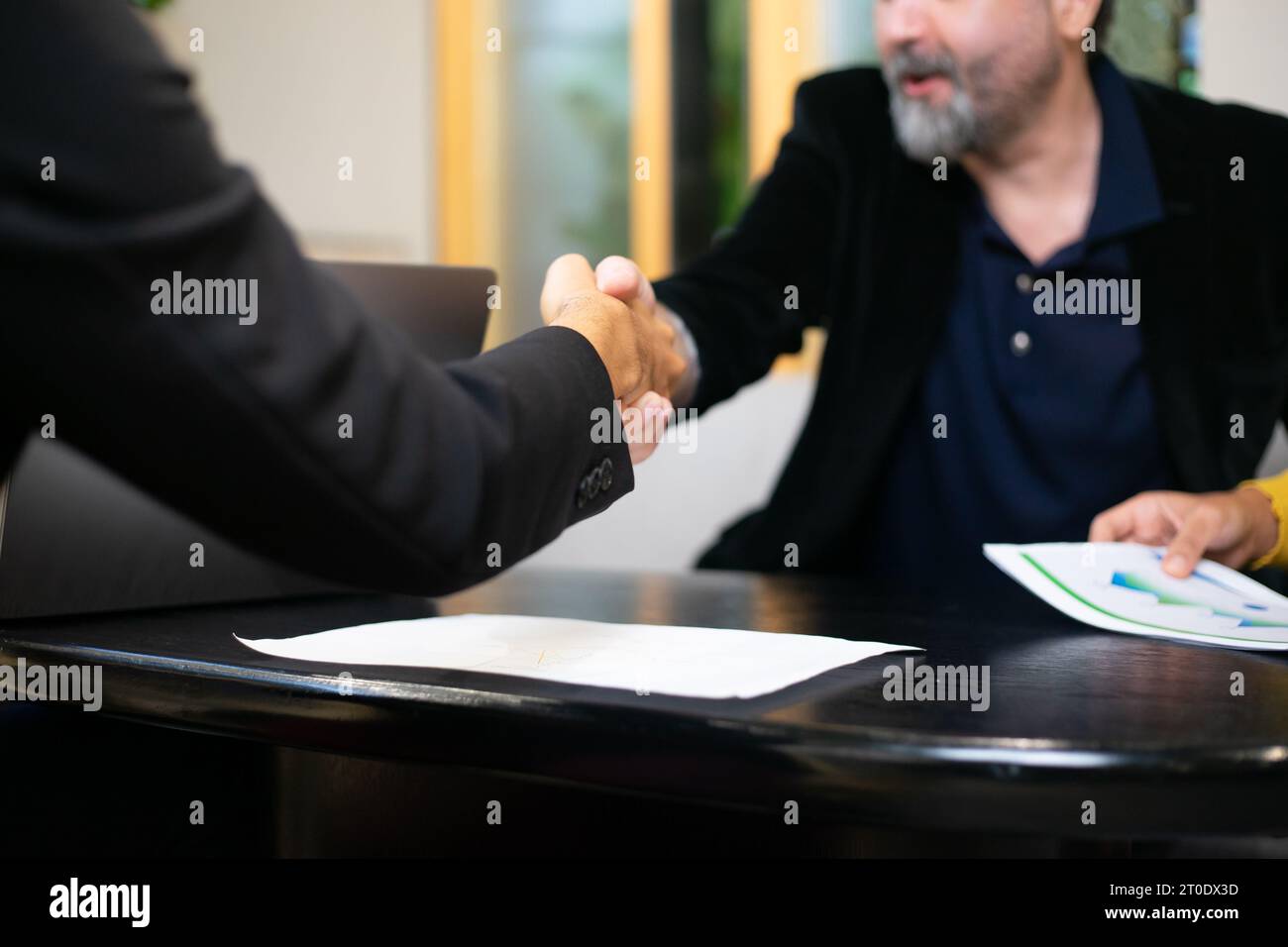 Geschäftsleute schütteln die Hände, nachdem sie ein Geschäftsvertragszeichen versiegelt haben. Gelegentliche Geschäftsverhandlungen im Büro. Teamarbeit und erfolgreiche Geschäfte Stockfoto