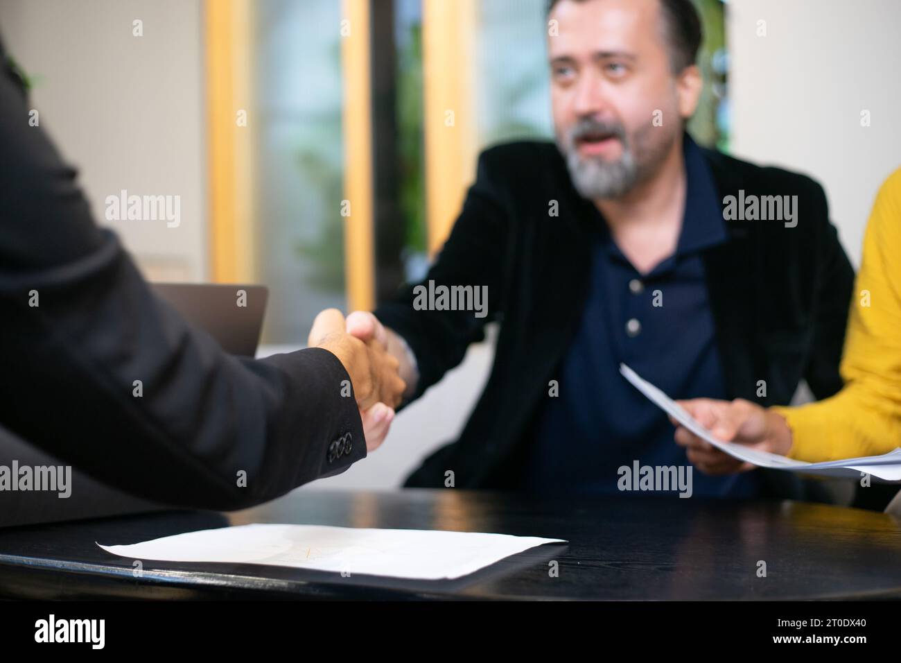 Geschäftsleute schütteln die Hände, nachdem sie ein Geschäftsvertragszeichen versiegelt haben. Gelegentliche Geschäftsverhandlungen im Büro. Teamarbeit und erfolgreiche Geschäfte Stockfoto