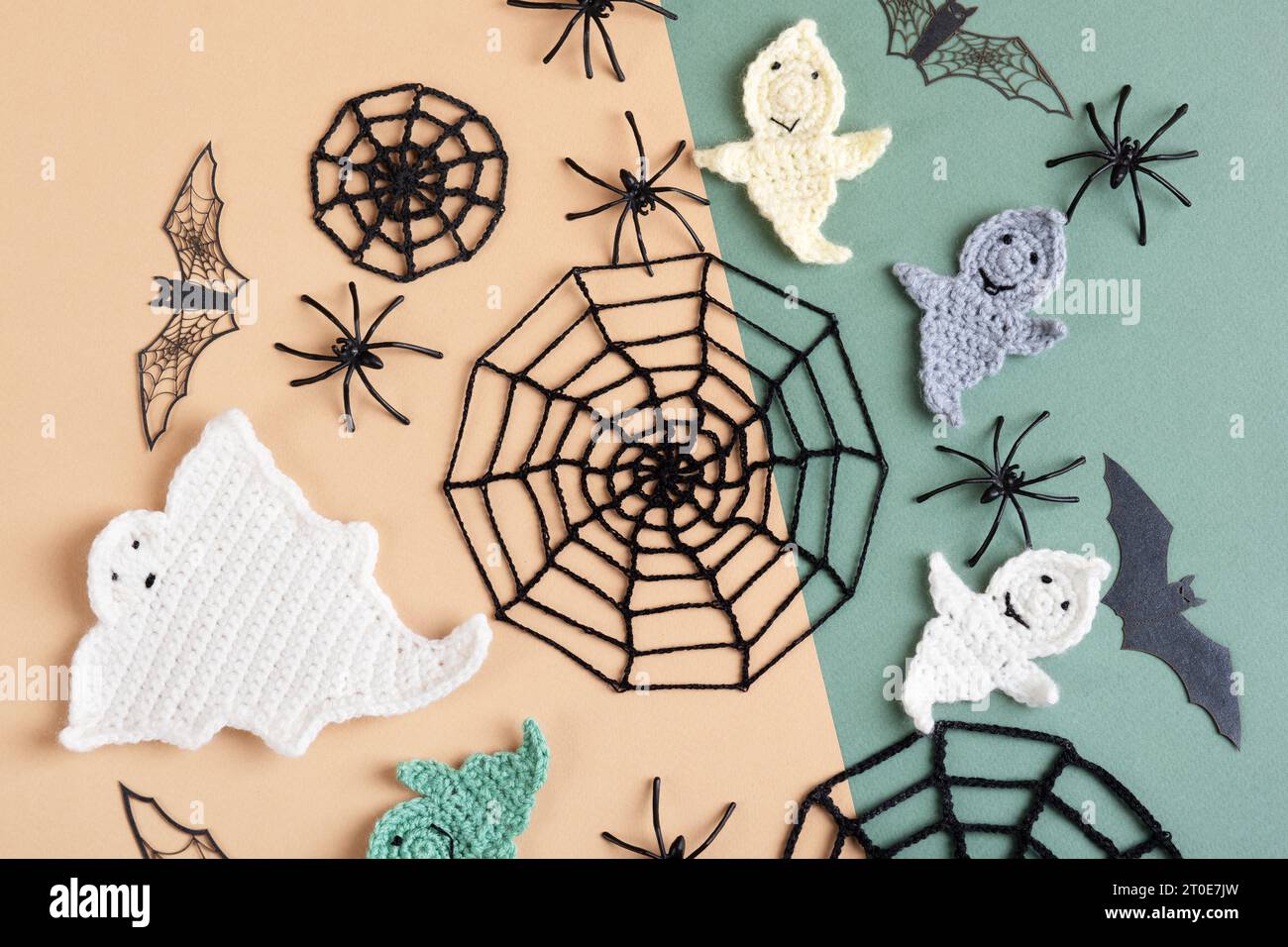 Halloween-Dekorationen, Geist, Spinnen, Fledermäuse, gestrickte Webs auf grünem und beigem Hintergrund. Flache Lage, Draufsicht Stockfoto
