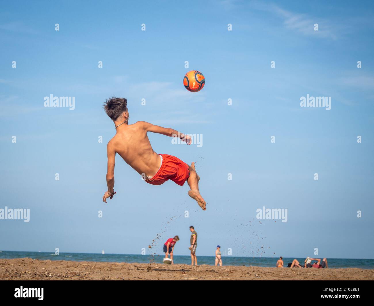 Junge am Strand, der Fußball spielt Stockfoto