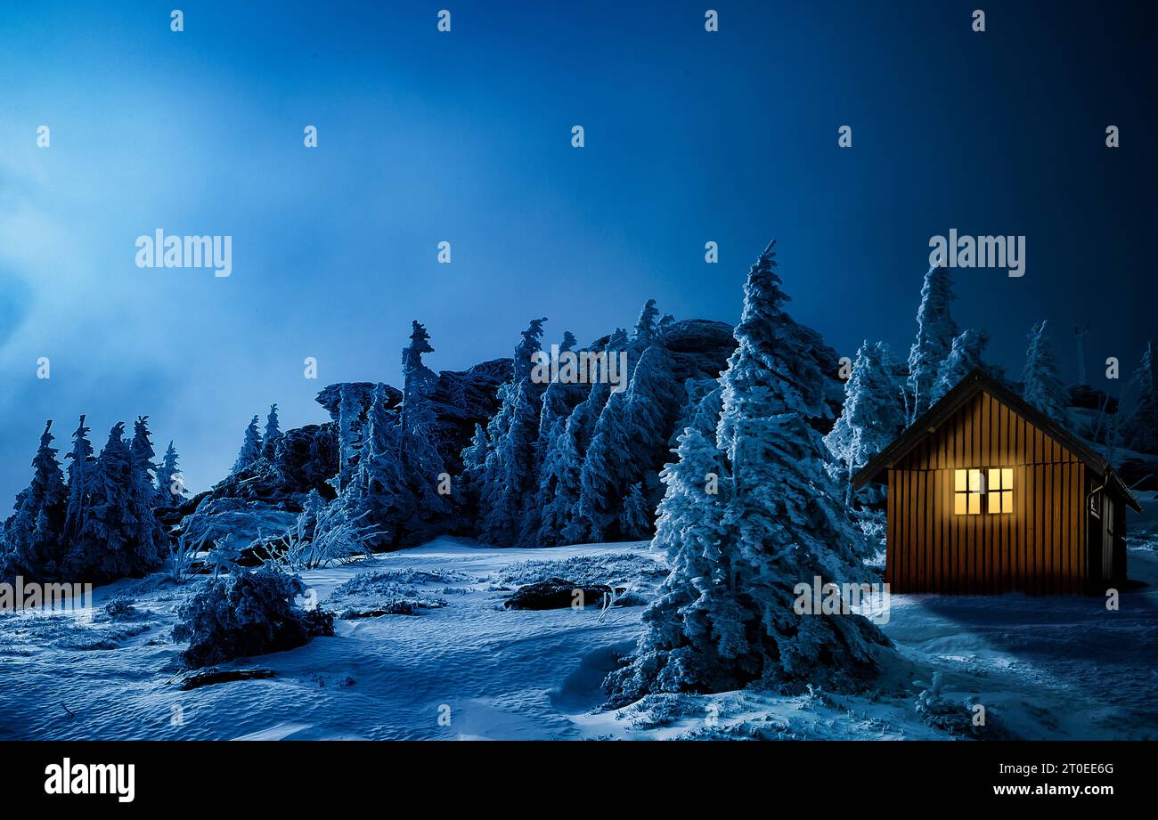 Weihnachtshütte mit beleuchtetem Fenster in einer verschneiten Winterlandschaft Stockfoto