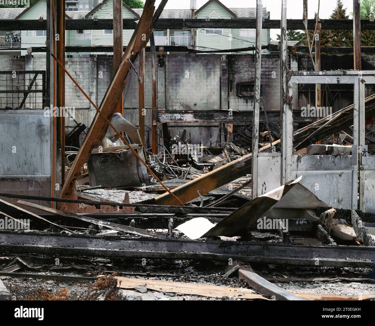 Das Gebäude brannte bis auf den Boden. Gerüststruktur des Gebäudes nach Totalschaden durch einen Brand Verkohltes, zusammengebrochenes Gebäude mit Holzbalken, gebogenem Metall und Stockfoto
