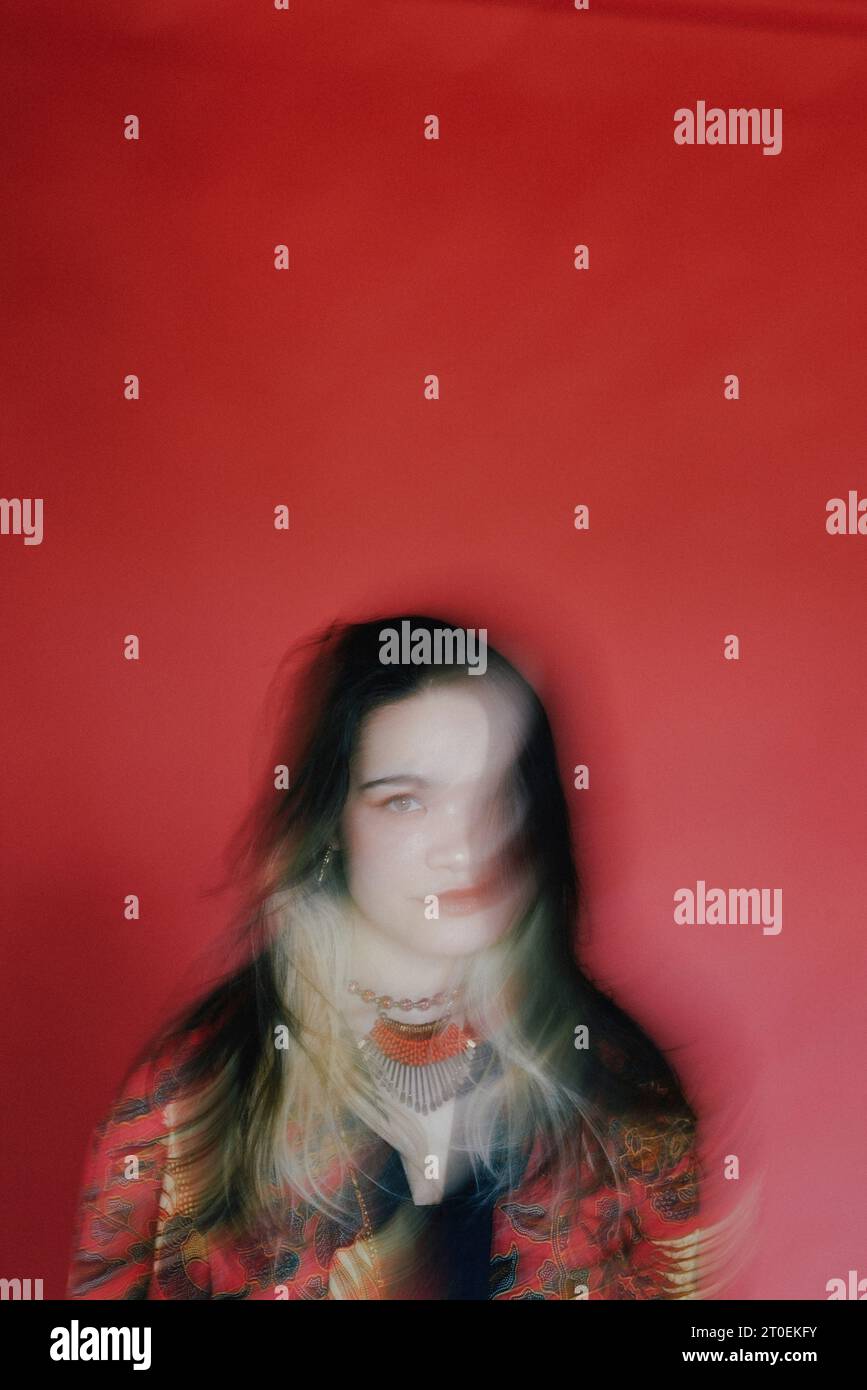 Porträt einer jungen Frau vor rotem Hintergrund mit Bewegungsunschärfe Stockfoto