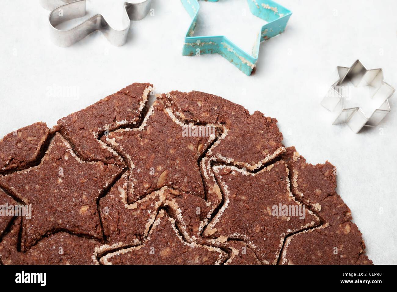 Ausgerollter Schokoladen-Keksenteig auf Pergamentpapier. Glutenfreies Mandelmehl Schokoladenkeks. Hintergrund zum Backen von Weihnachtskeksen. Schweizer Rezept „Basler B Stockfoto