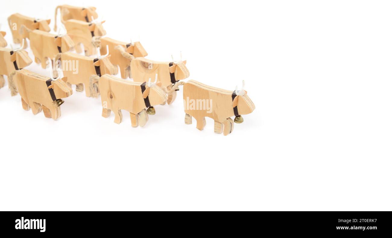 Kuh vor einer Gruppe von Kühen, die einen Pfeil von oben links nach rechts bilden. Gewinnen, Führen, herausragendes Konzept. Handgefertigte Holzkuh-Silhouetten Stockfoto