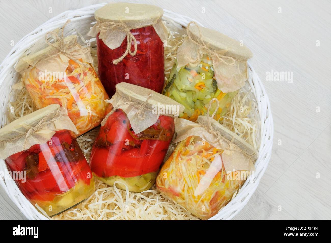 Verschiedene Glasgläser mit hausgemachtem eingelegtem oder fermentiertem Gemüse in Box auf weißem Hintergrund. Fermentierte Lebensmittel. Platz für Text. Draufsicht. Stockfoto