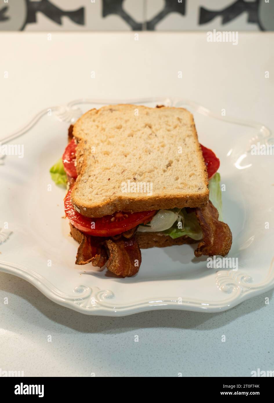 BLT, ein Sandwich mit Speck, Tomaten und Salat, das mit Hafernußbrot auf einem weißen Teller serviert wird. USA. Stockfoto