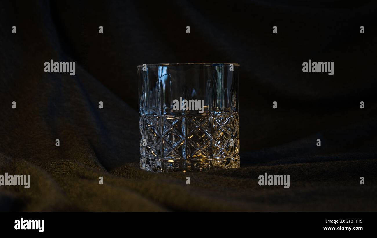 Ein einsames Glas Whiskey, vor einem eleganten grau-schwarzen Hintergrund, verkörpert Raffinesse und die Essenz des kontemplativen Stockfoto