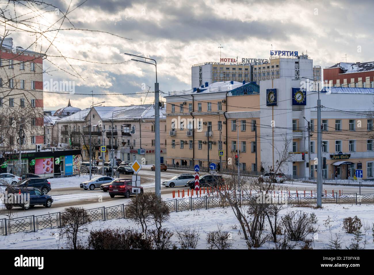Die Straßen von Ulan-Ude, Burjatiya, Russland, mit dem Verkehr und Hotel 'Burytiya' während des hellen Wintertages. Stockfoto