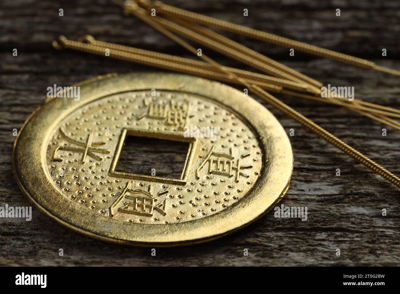 Akupunkturnadeln und alte Münze auf Holztisch, Großaufnahme Stockfoto