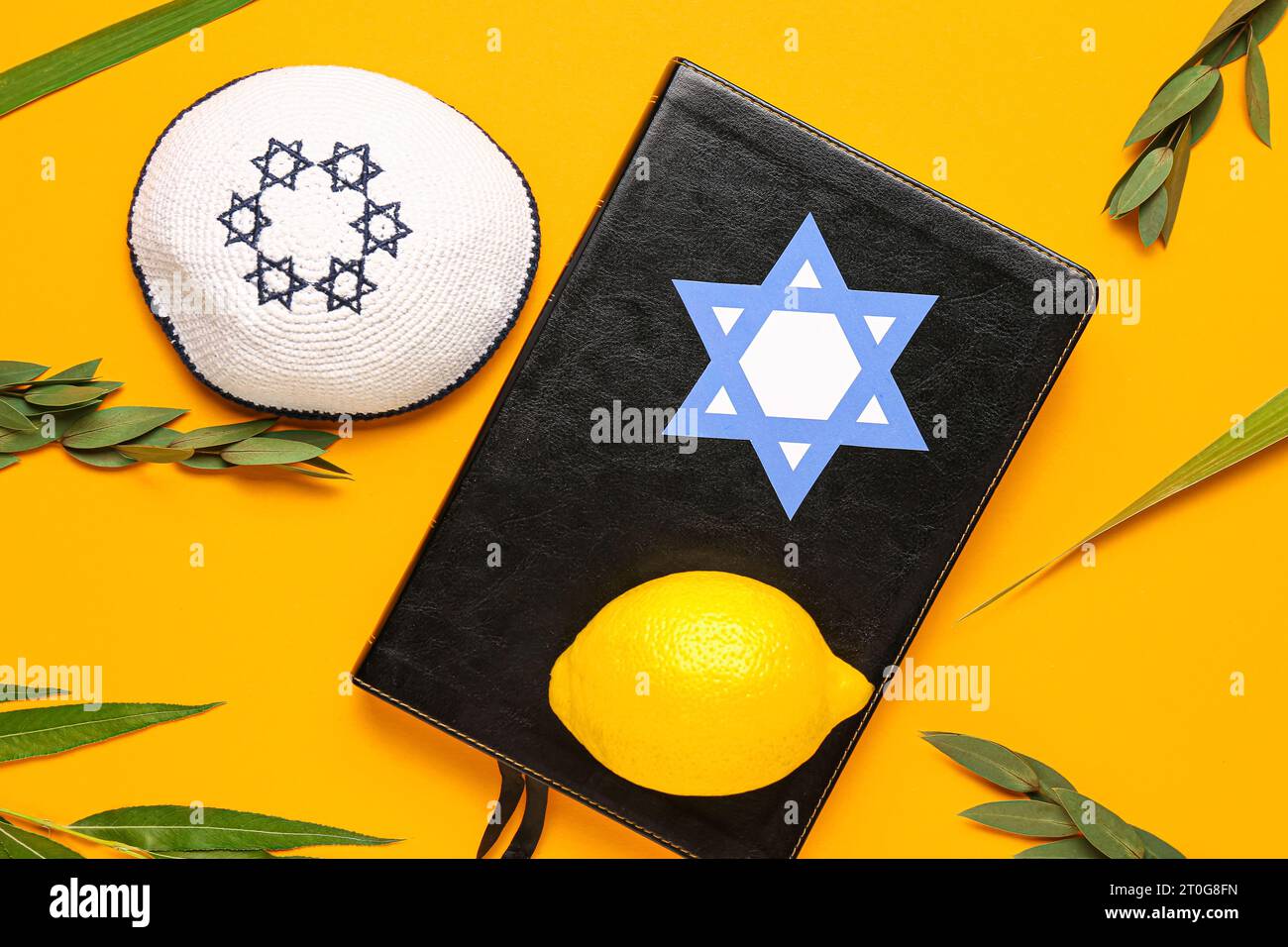 Vier Arten (Lulav, hadas, arava, etrog) als Sukkot-Festival-Symbole, Kippah und Torah auf orangem Hintergrund Stockfoto