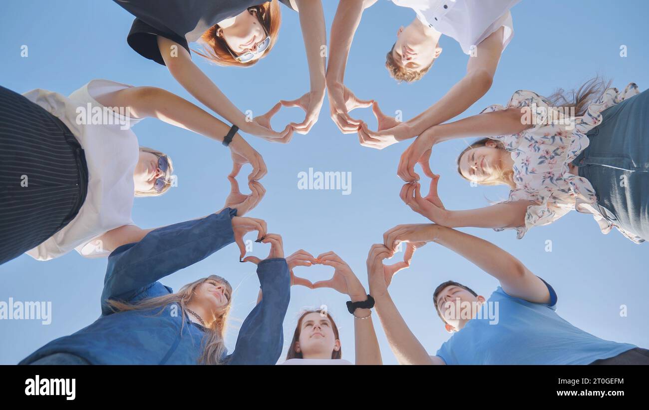Gruppe von sieben Personen, die zusammen ein Herz mit ihren Fingern und Händen machen - Menschen im Cricle, die Spaß haben und spielen - Bodensicht. Stockfoto