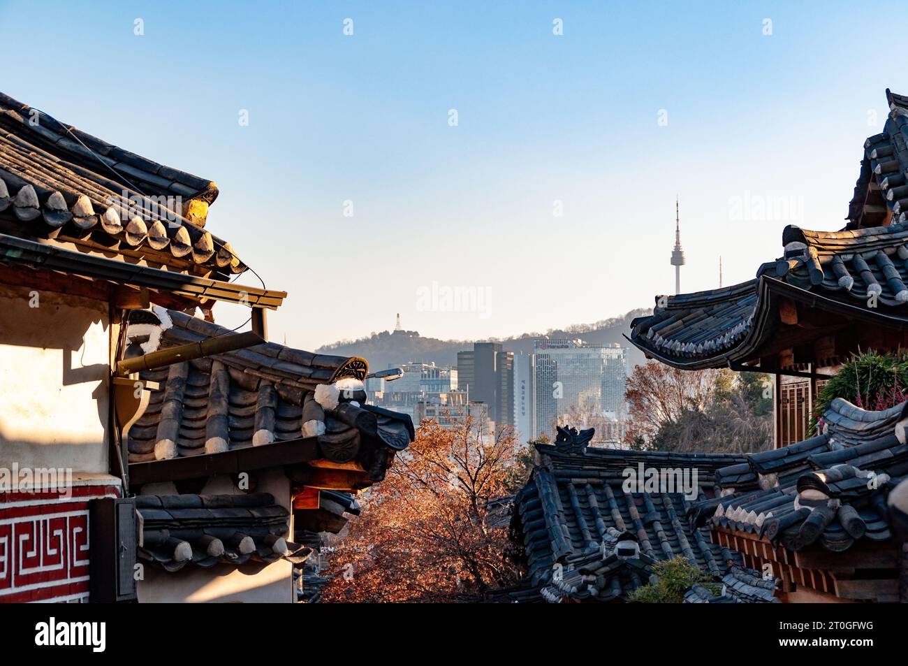 Traditionelle koreanische Dächer im Bukchon Hanok Village in Seoul, Südkorea, mit Stadt und Turm im Hintergrund Stockfoto