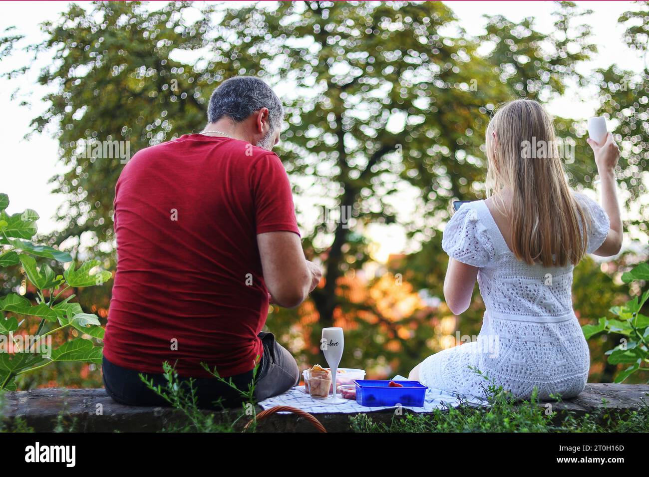 Ein Paar sitzt mit Weingläsern und hat Spaß, sich bei Sonnenuntergang im Hinterhof zu unterhalten. Verbringen Sie Sommerzeit und feiern Sie eine Party im Freien Stockfoto