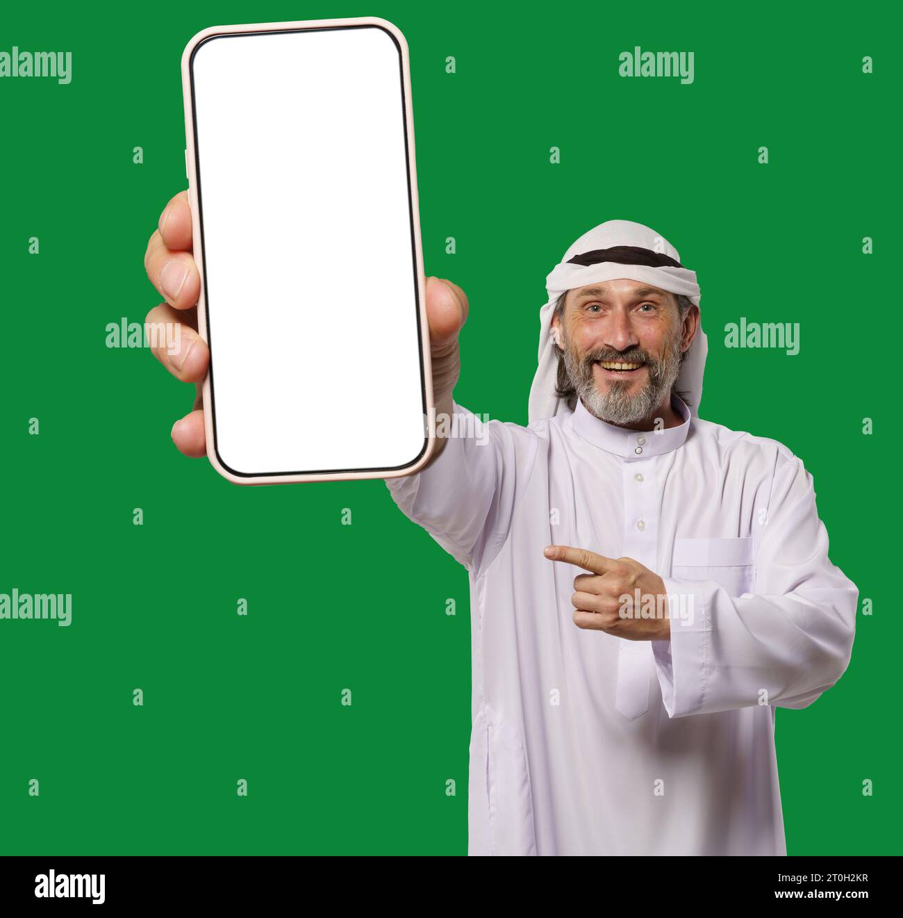 Der arabische Mann lächelt und zeigt ein Mobiltelefon mit leerem weißen Display, das Kopierraum für App-Werbung, -Dienste und -Informationen bietet. Glücklicher Mann, isoliert vor grünem Hintergrund. . Hochwertige Fotos Stockfoto