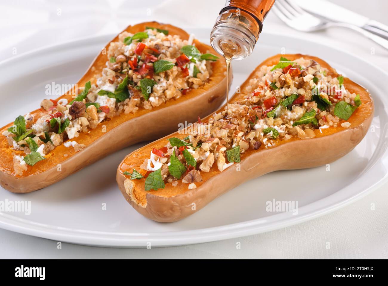 Gebackener gefüllter Kürbis gefüllt mit Walnüssen, frischer Minze und Chili mit Quinoa Tabbouleh. Der Ahornsirup macht sie ausgezeichnet. Es ist eine gesunde Beilage Stockfoto