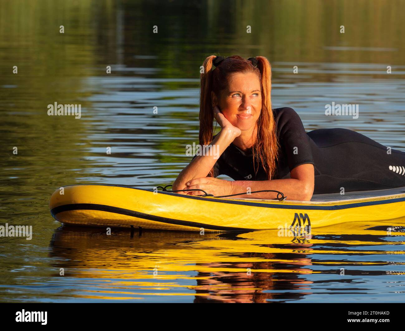 Frau, die entspannt auf dem Stand-up-Paddle-Board im See liegt Stockfoto